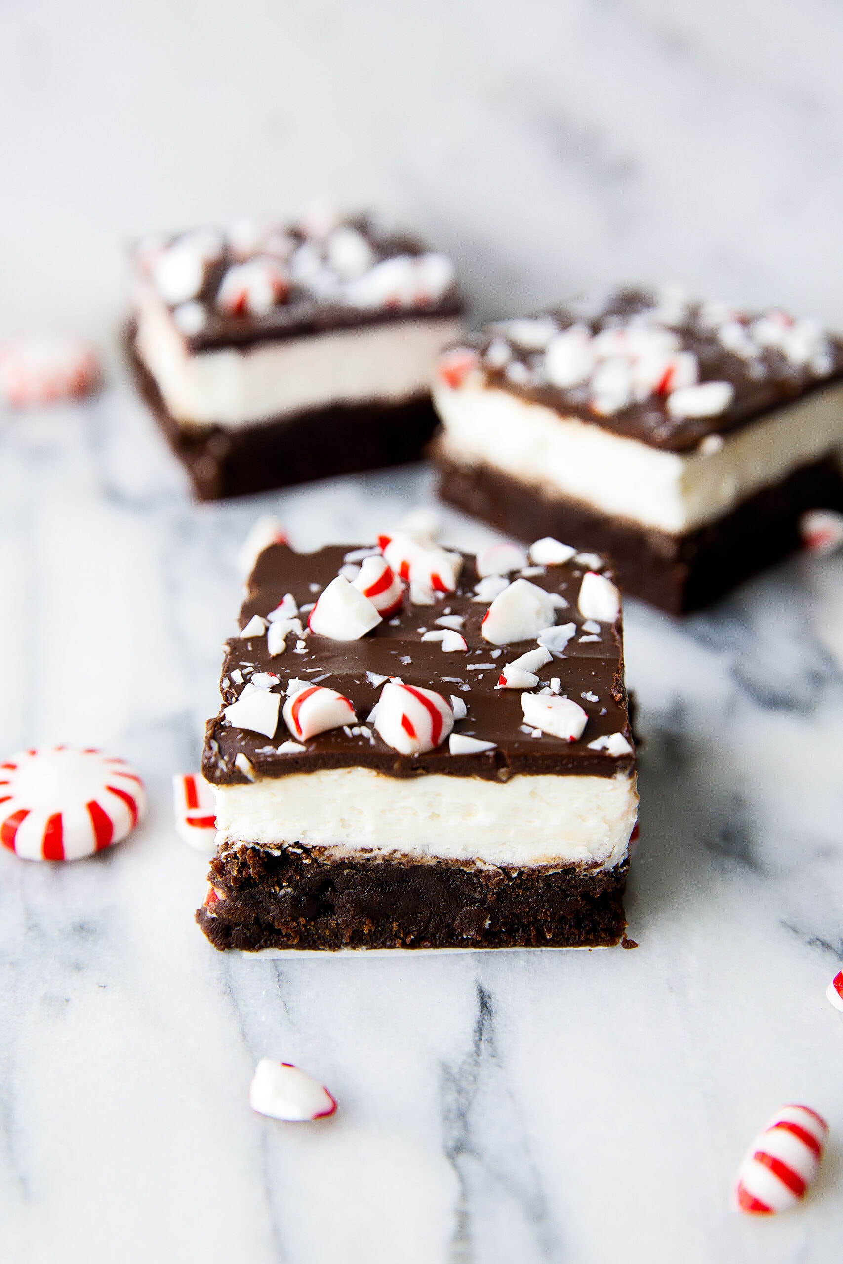 Rich and fudgy peppermint-infused brownies are topped with a fluffy peppermint frosting and chocolate bark. The ultimate holiday treat in our home. I guarantee it will be in yours, too! | via Broma Bakery