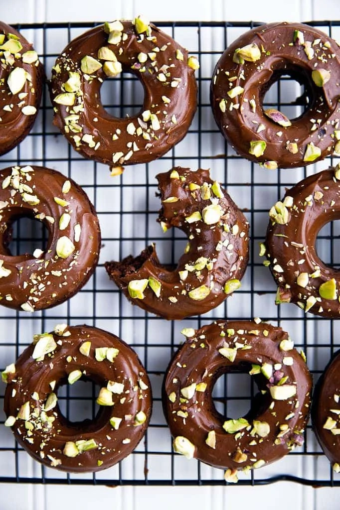 Baked chocolate cake donuts topped with a chocolate glaze and sprinkled with crunchy pistachios. Perfect for a weekend breakfast with family.