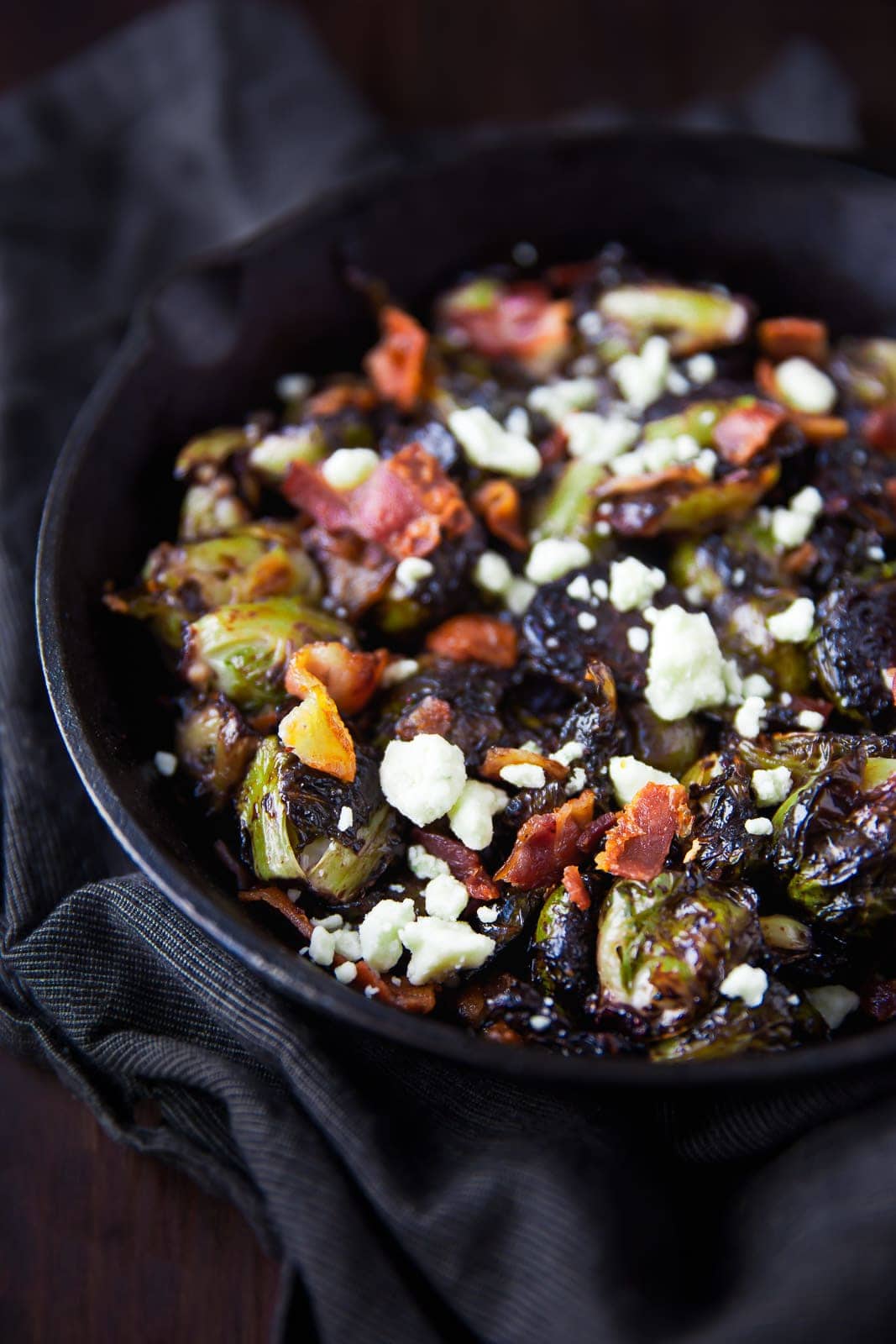 Oven roasted brussels sprouts with a blueberry balsamic glaze tossed with bacon and blue cheese makes for a delectable addition to your holiday table!