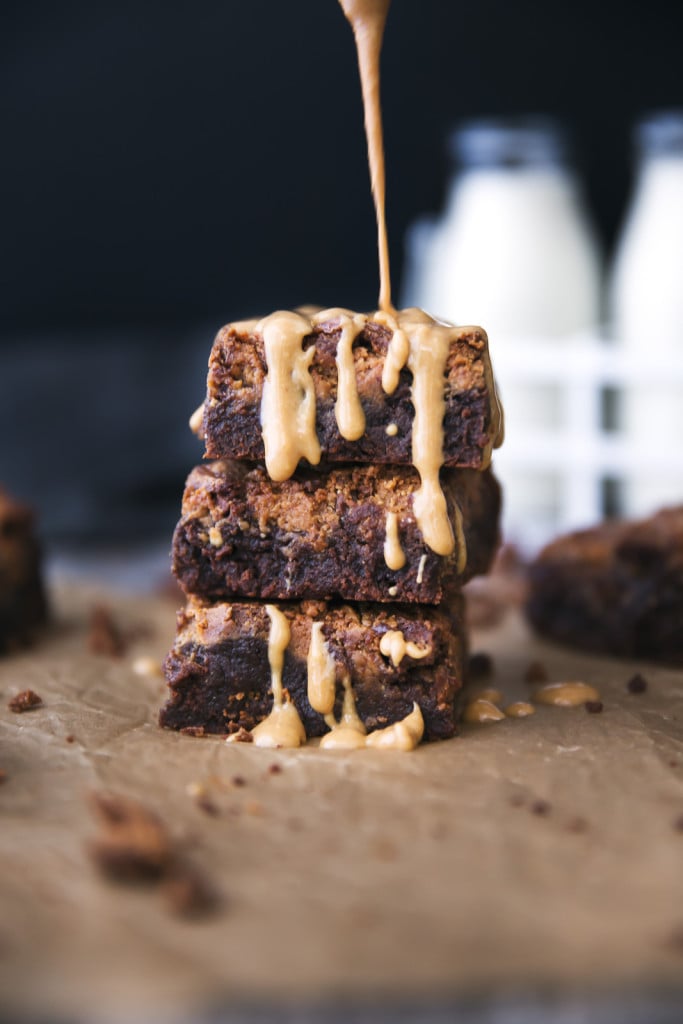 drizzling peanut butter onto a stack of Fudgy Peanut Butter Brownies 
