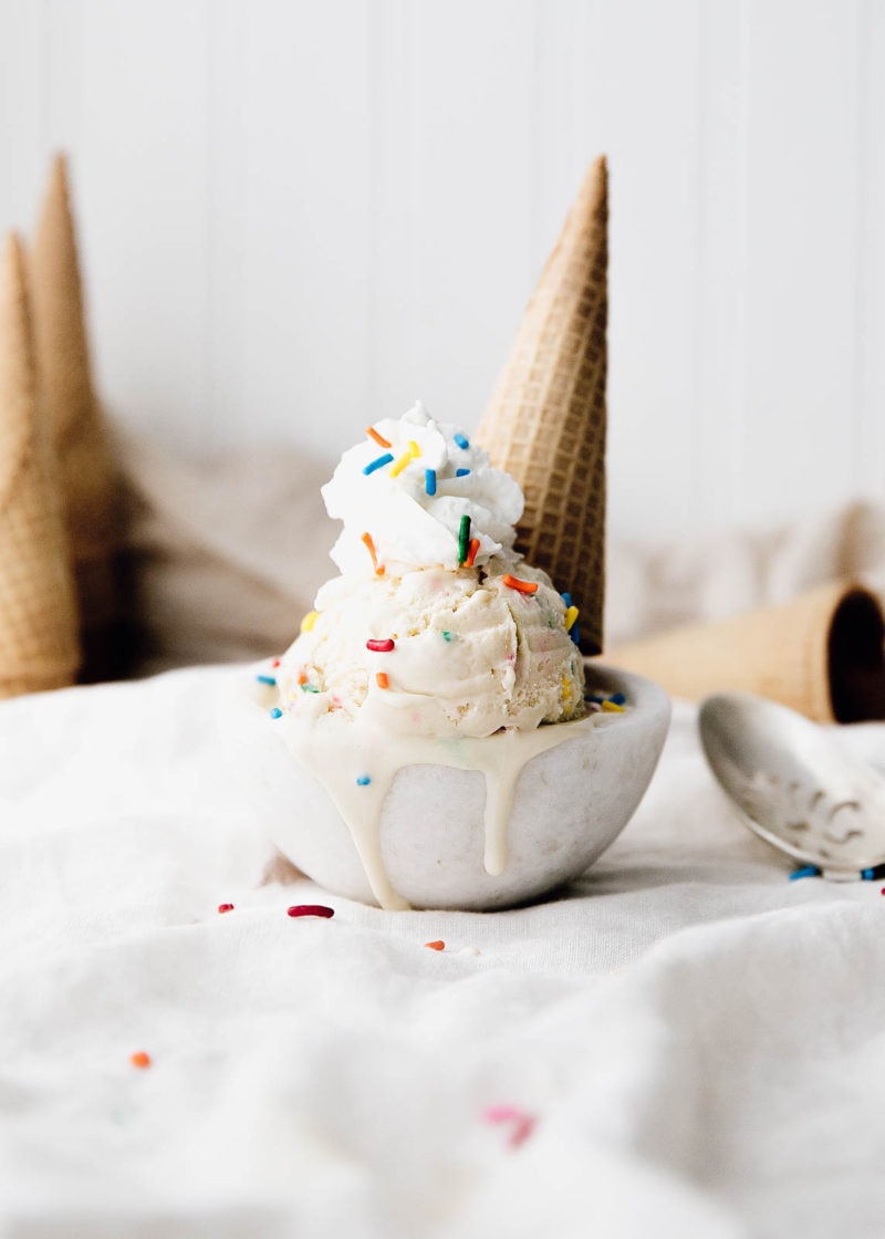 Cake Batter Ice Cream in a bowl topped with whipped cream and a cone
