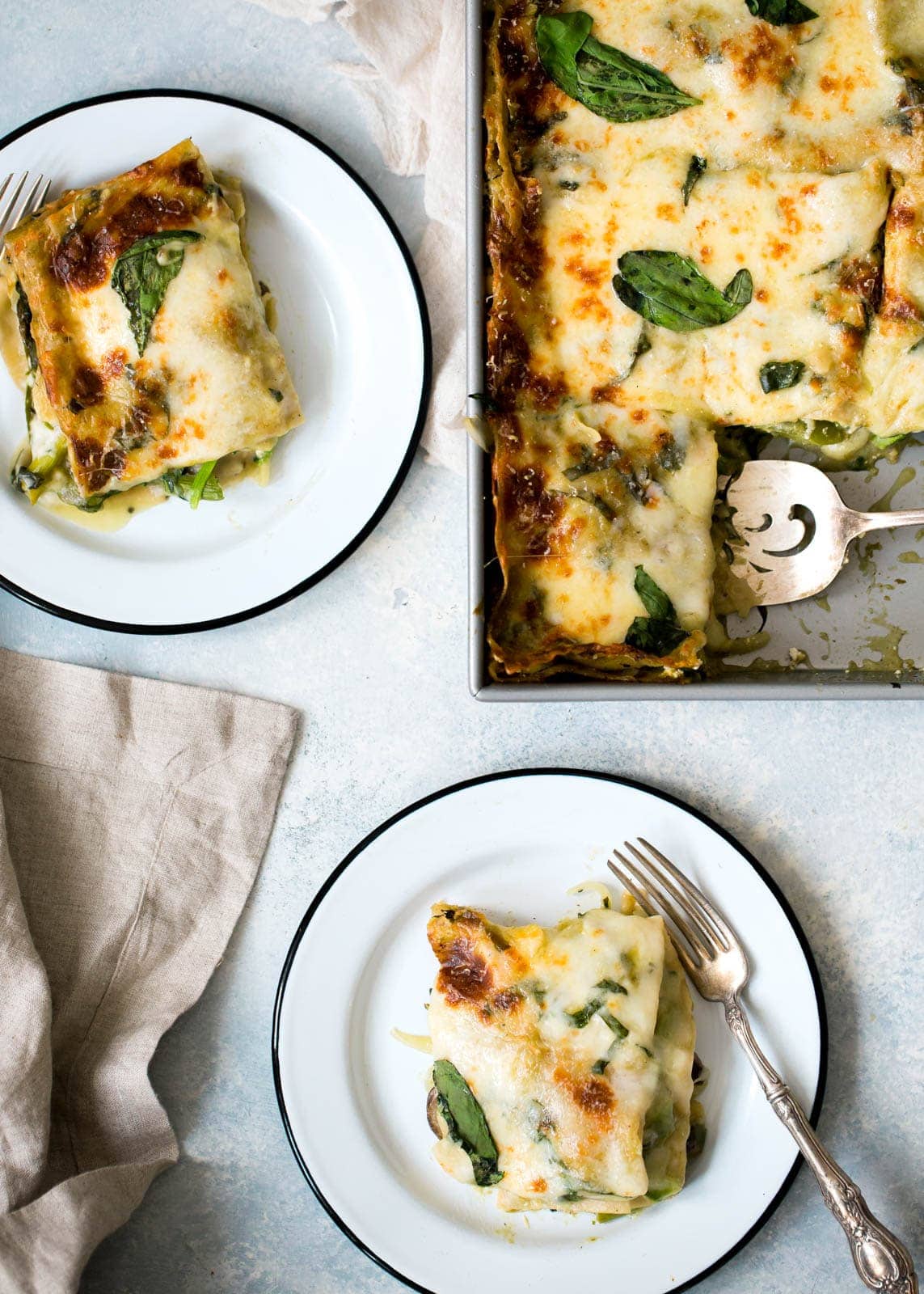 Vegetarian Green Lasagna slices on plates next to pan of lasagna