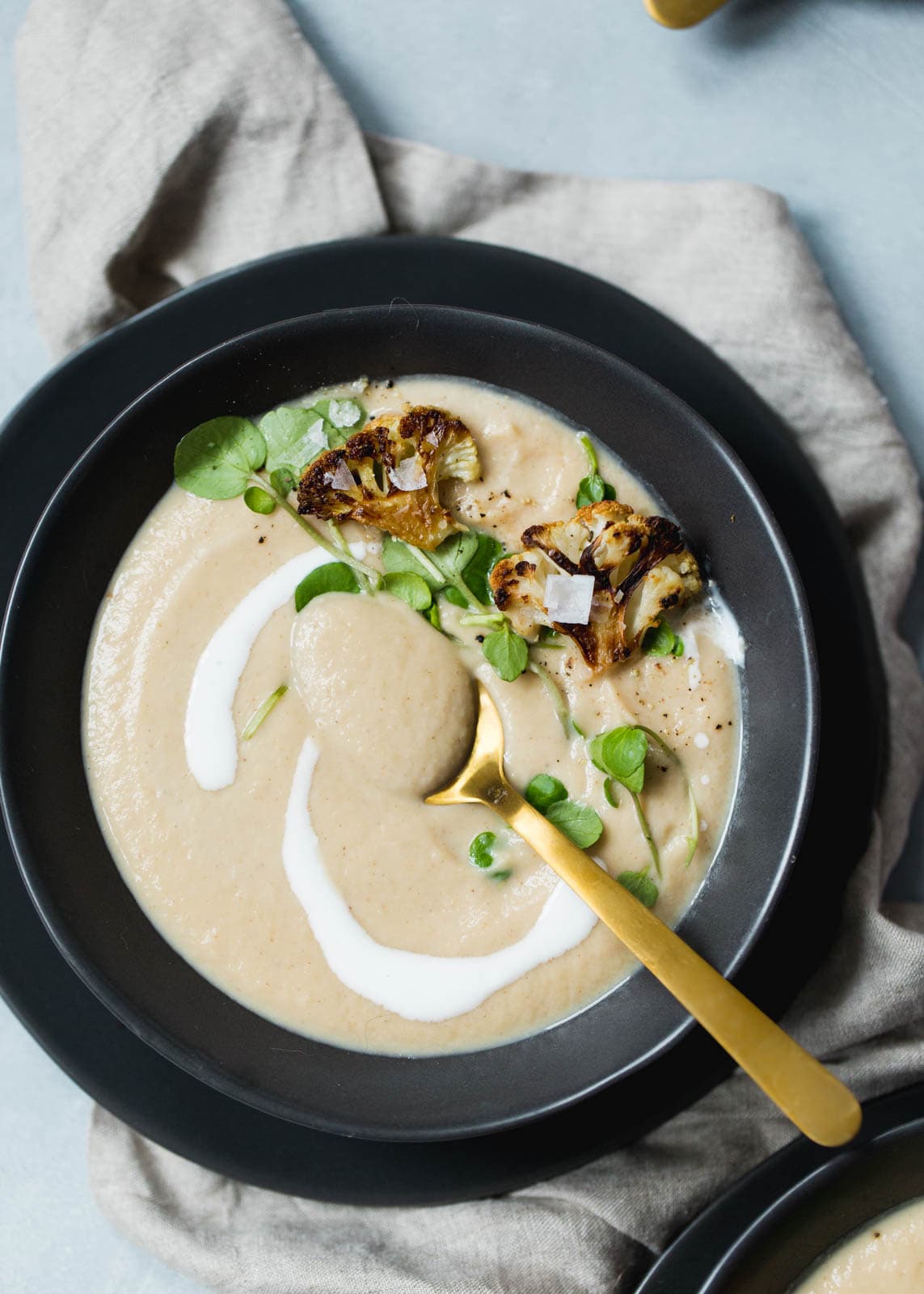 Creamy Roasted Cauliflower Soup in bowl with gold spoon