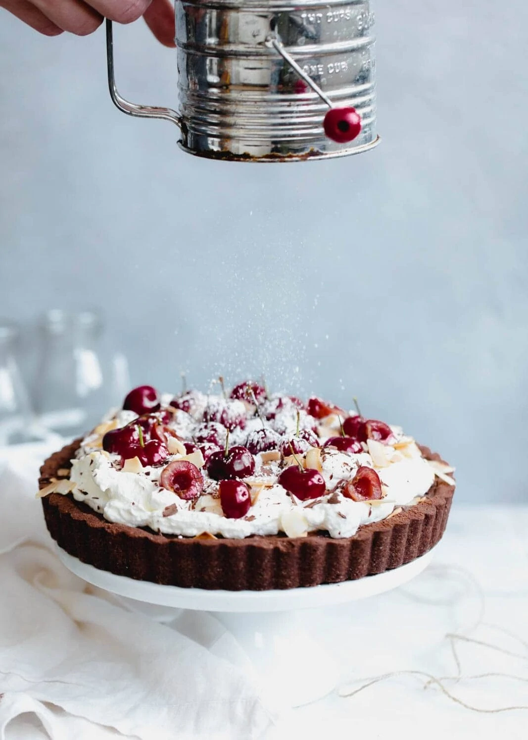 A take on Black Forest Cake, this fudge-like chocolate cherry tart is topped with whipped cream, toasted coconut, and fresh cherries.