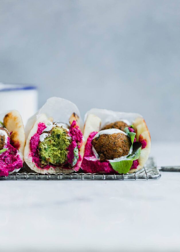 Homemade green falafel filled with spinach and garden herbs, smothered between beet hummus, yogurt, and pita.