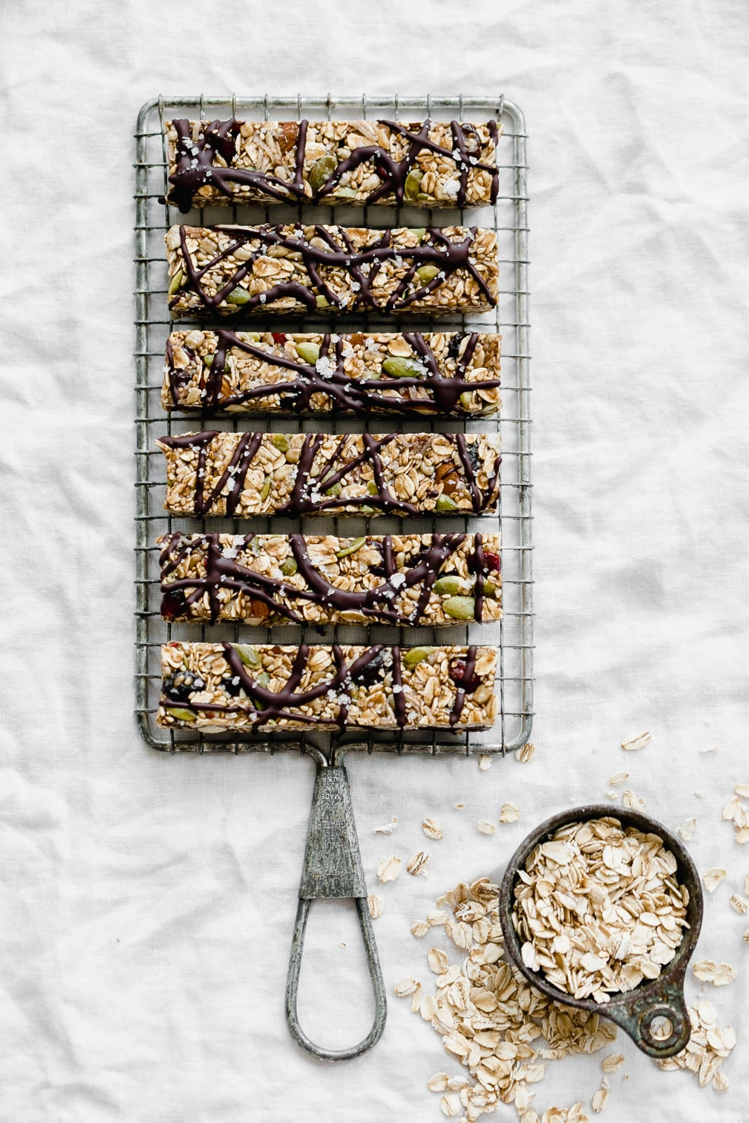 Raw Seedy Granola Bars made with oats, sunflower seeds, pepitas, sesame seeds, almonds, apricots, and honey, topped with a drizzle of dark chocolate