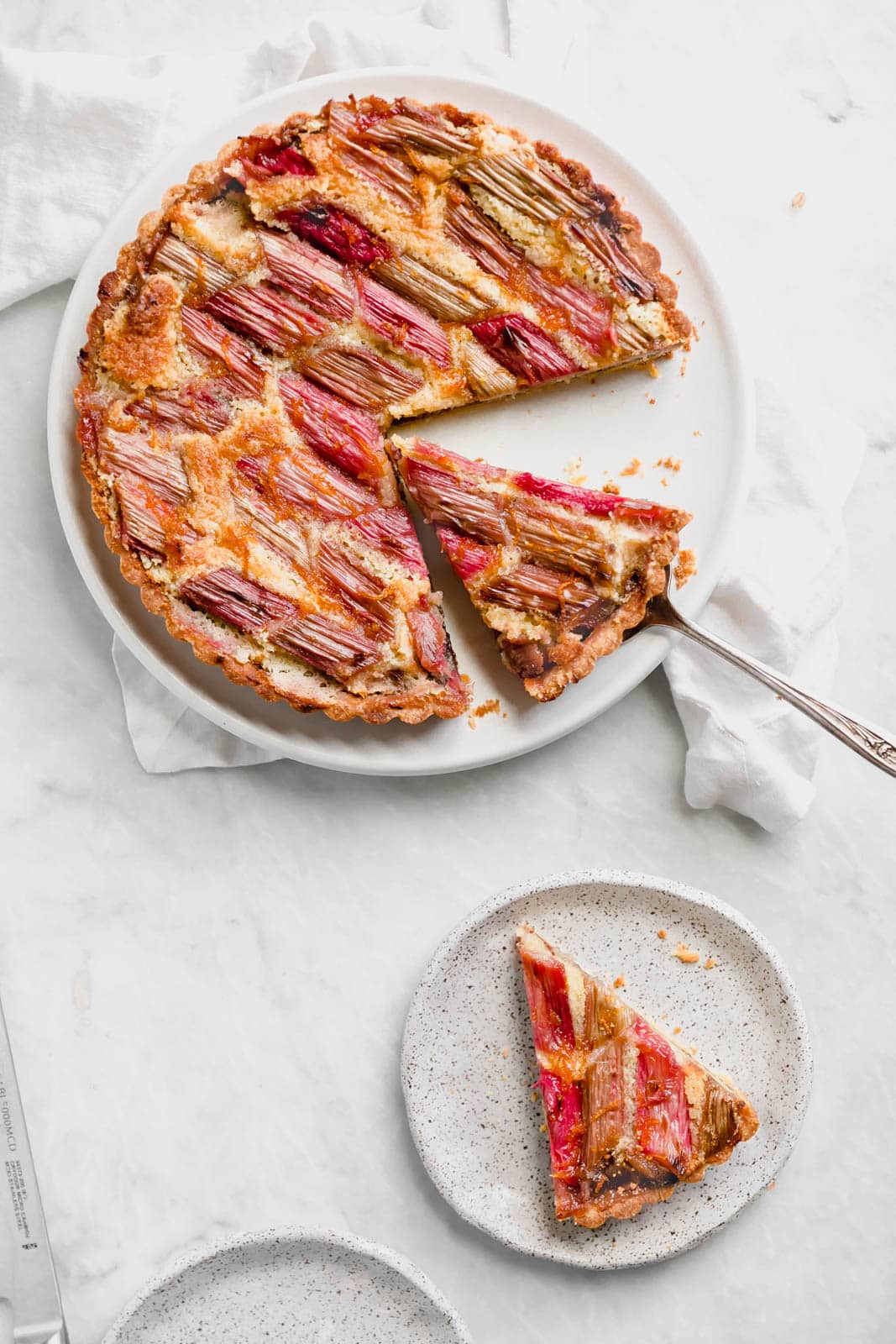The most showstopping Rhubarb Bakewell Tart made with a pâte sucrée crust, strawberry preserves, almond frangipane, and an orange-soaked rhubarb top