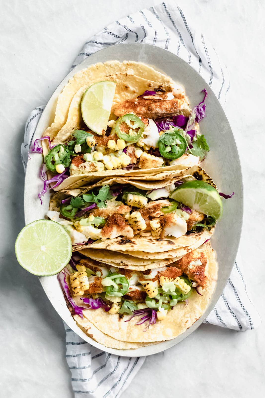 My go-to recipe for Taco Tuesday fish tacos: flakey blackened fish, cabbage, charred corn, jalapeños, and a “creamy” dairy-free avocado cilantro crema! 