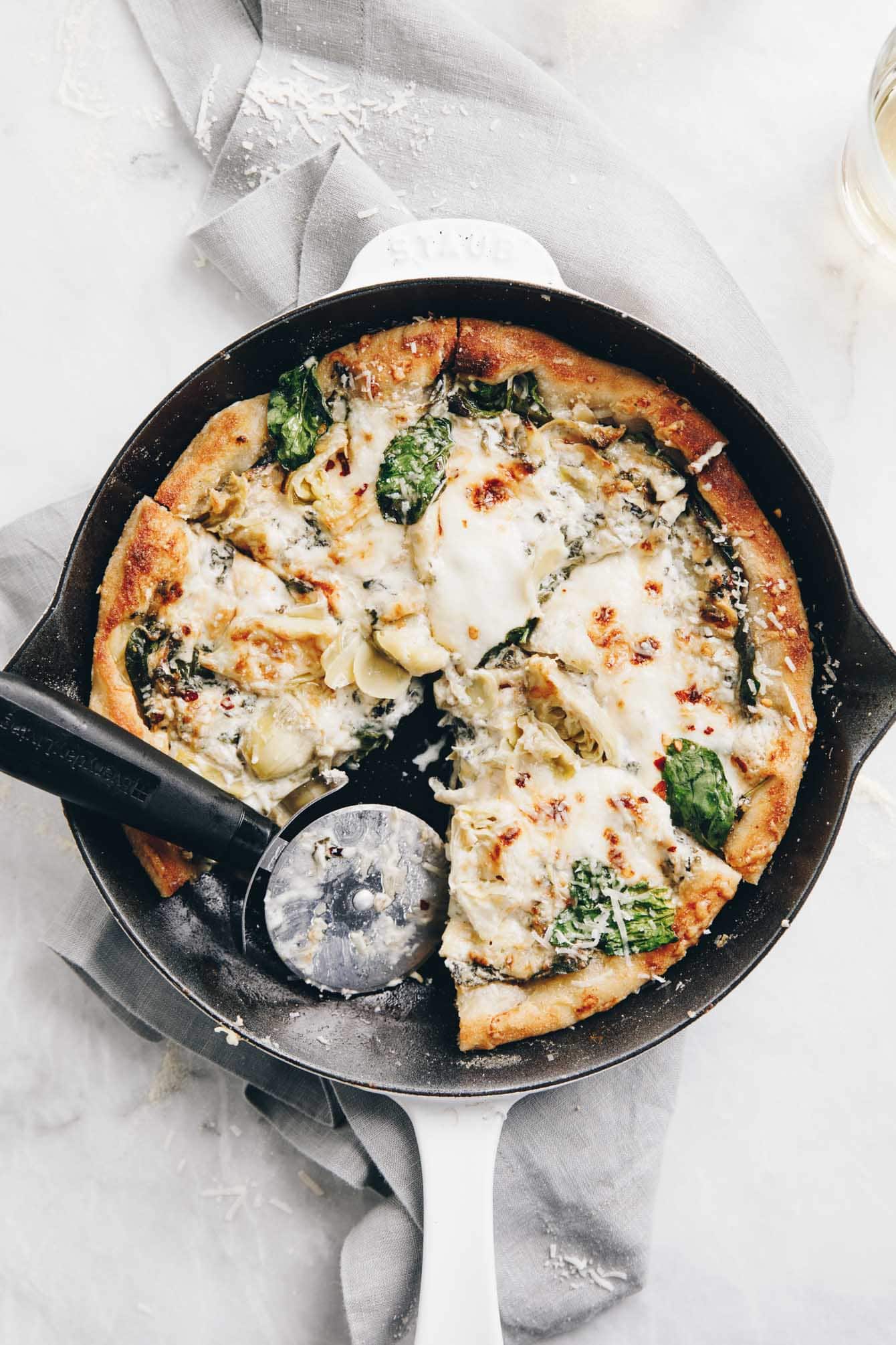 easy cheesy spinach artichoke pizza on a cast iron pan