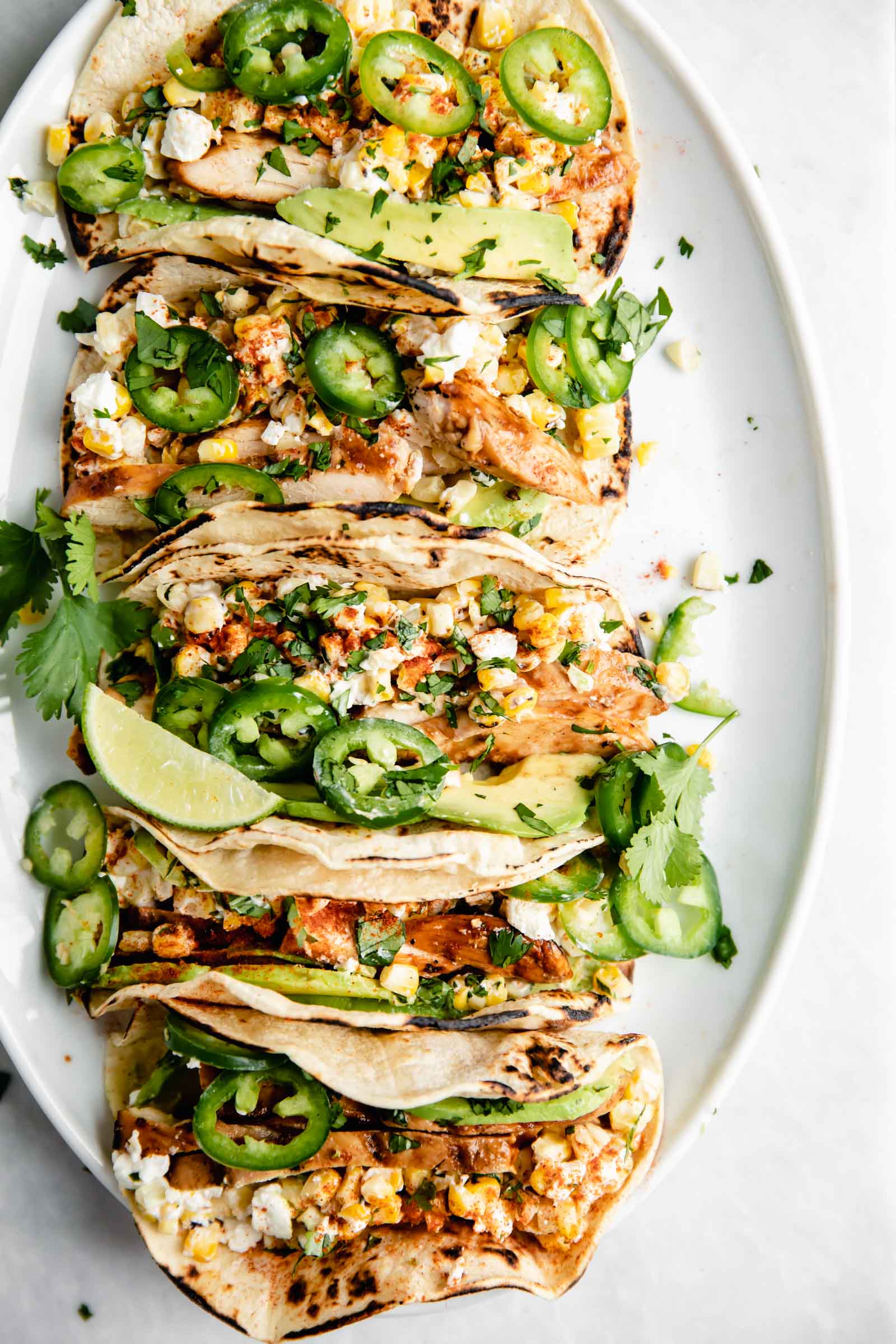 Kicking off Summer Taco Tuesdays with BBQ Chicken Mexican Street Corn tacos loaded with crema, cotija cheese, avocado, and fresh corn. Sign me up!