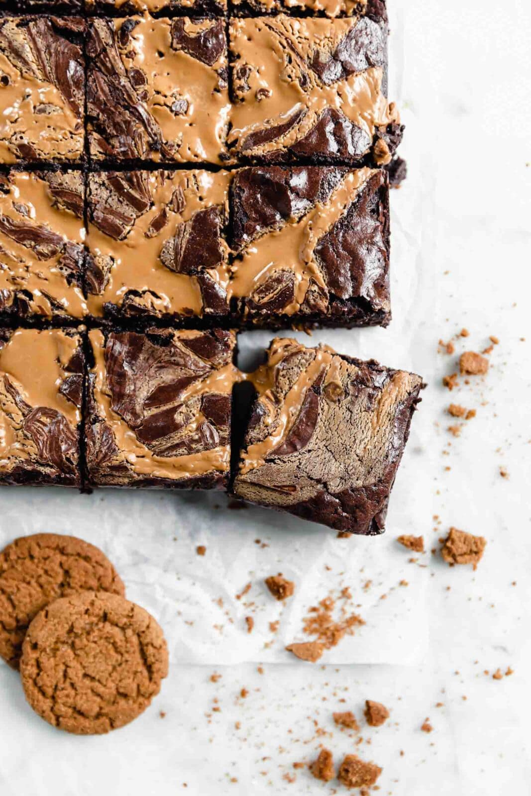 cookie butter swirled brownies on parchment paper with cookie crumbs