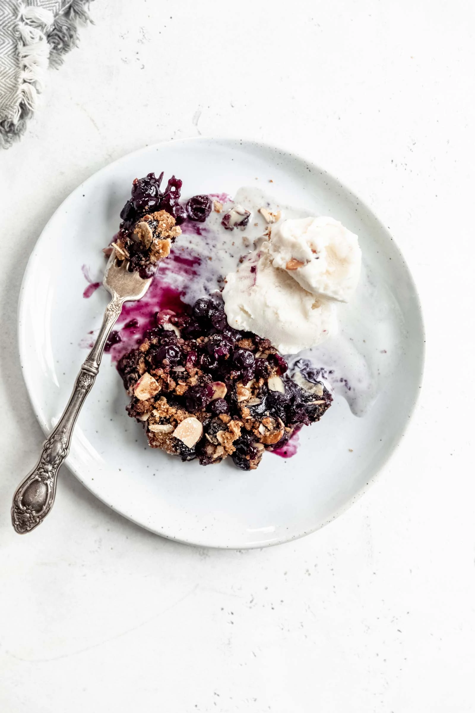 plate of gluten free blueberry crisp with coconut ice cream