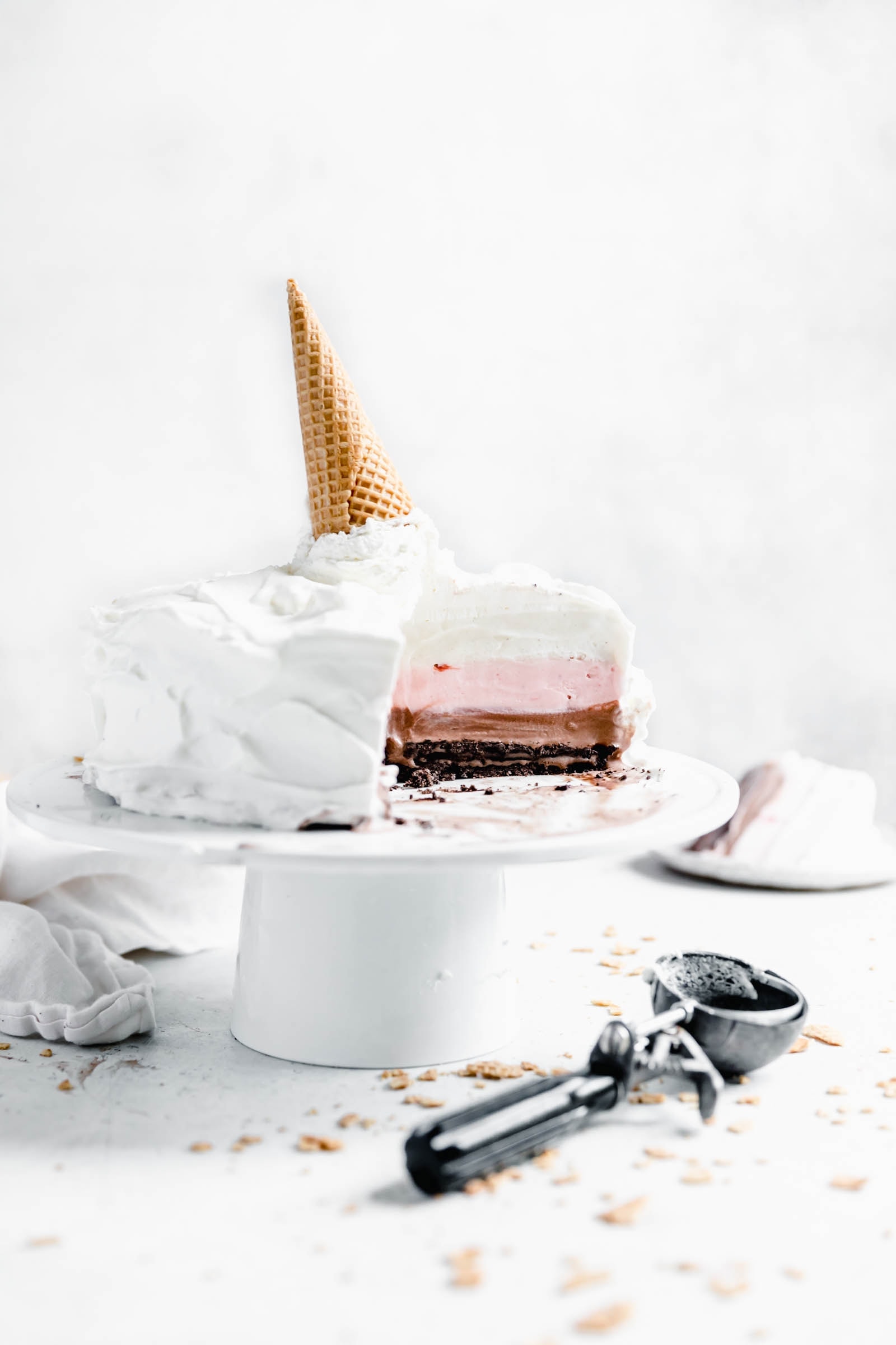 Neapolitan ice cream cake on cake stand with cookie scoop