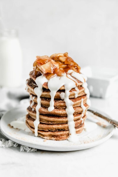 stack of apple cider donut pancakes topped with icing and cooked apples