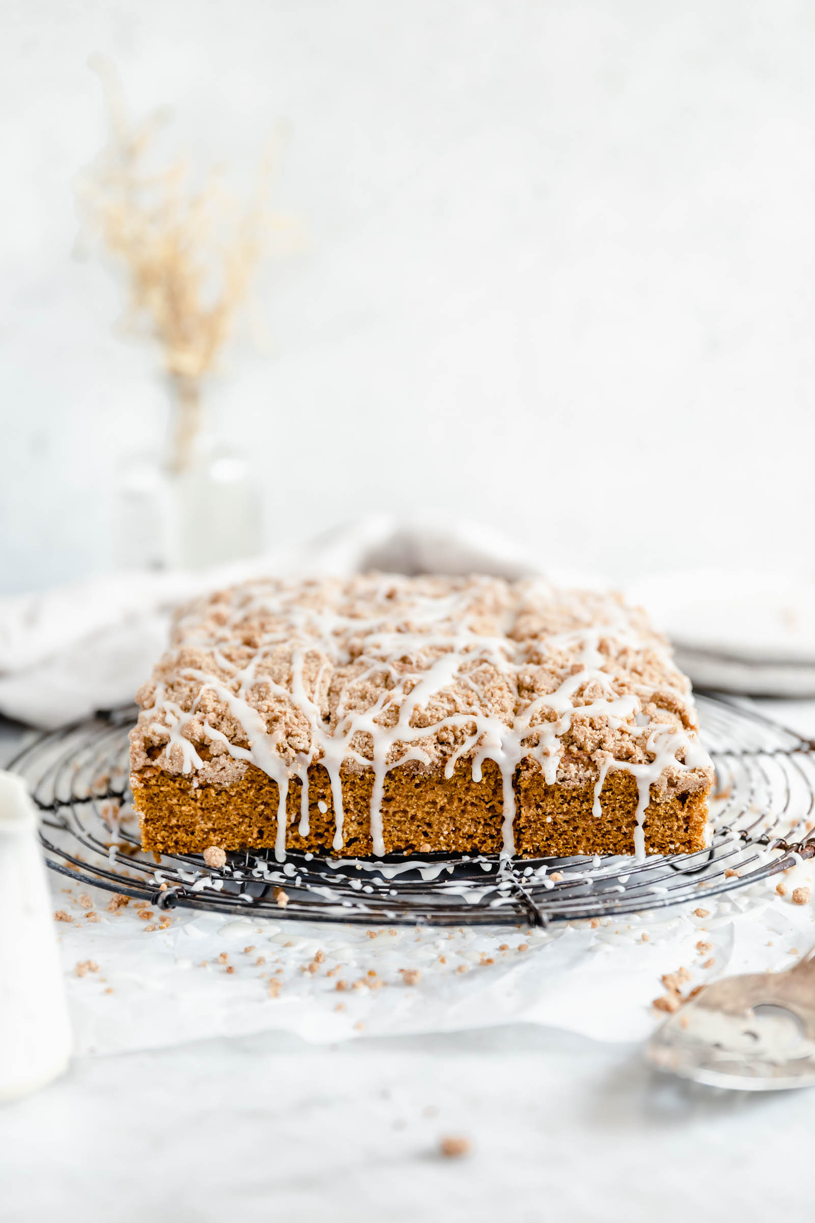 pumpkin coffee cake with crumb topping and cream cheese glaze on a cooling rack
