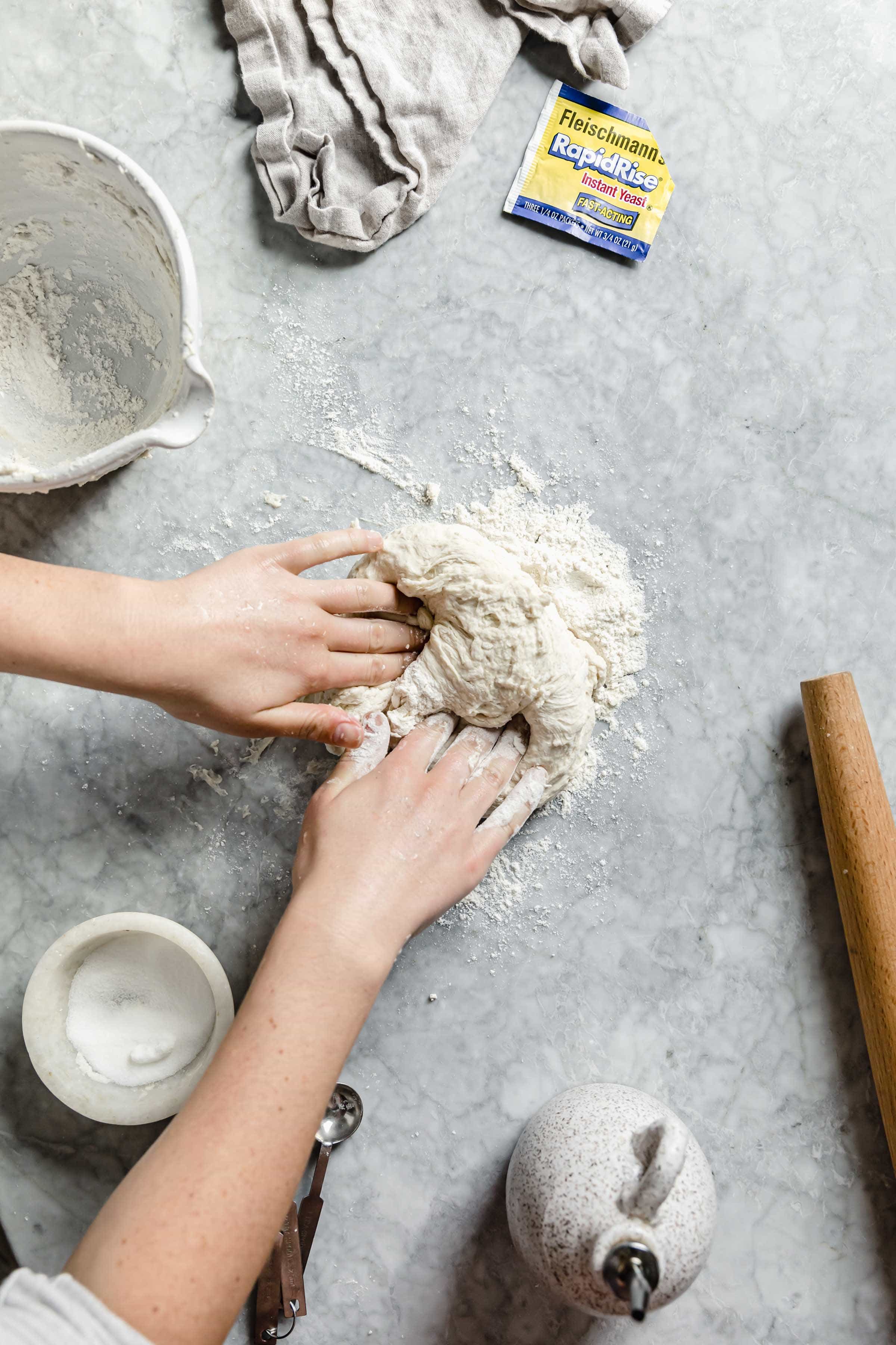 kneading pizza dough with hands on floured surface