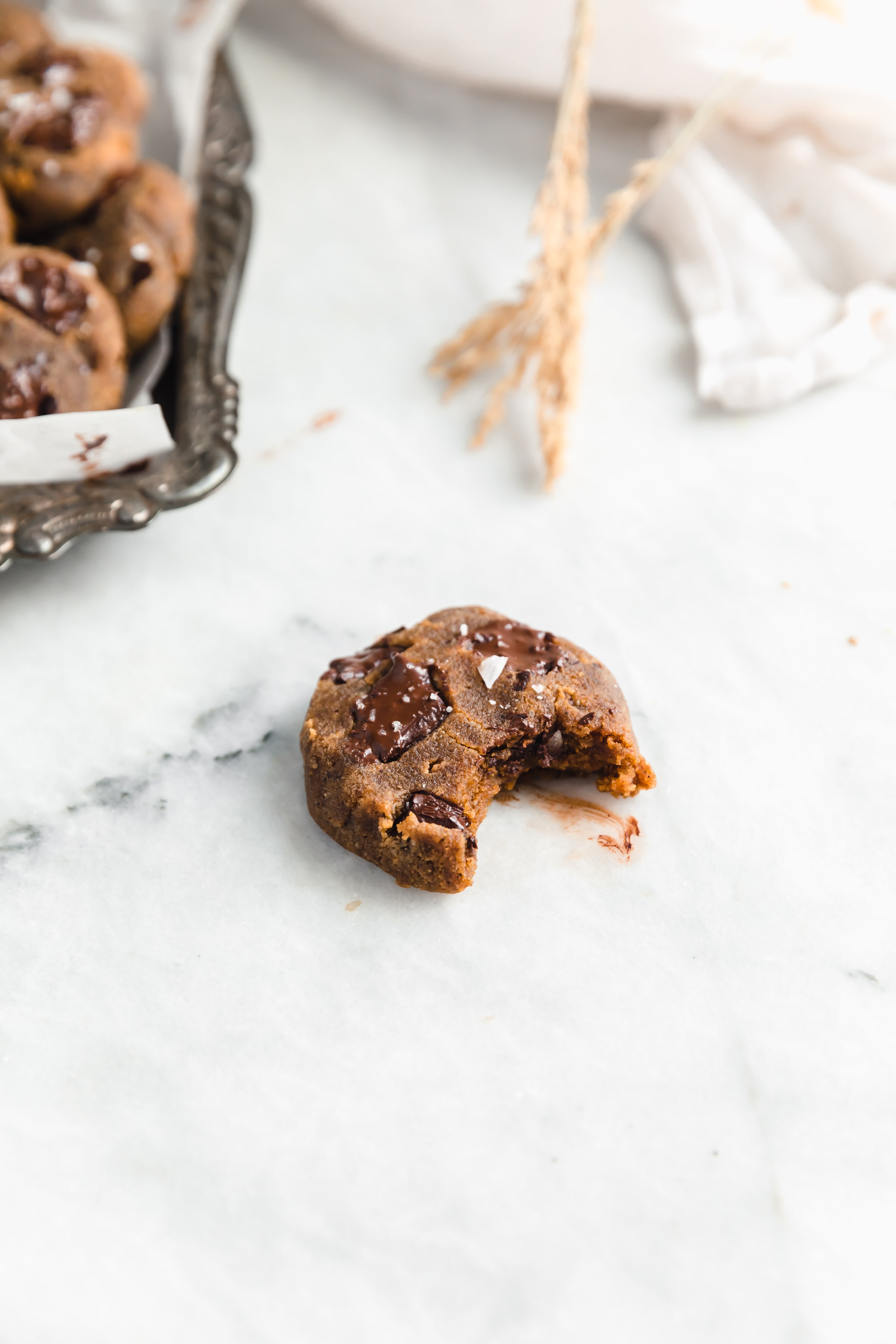 paleo pumpkin chocolate chip cookie with a bite taken out on marble counter