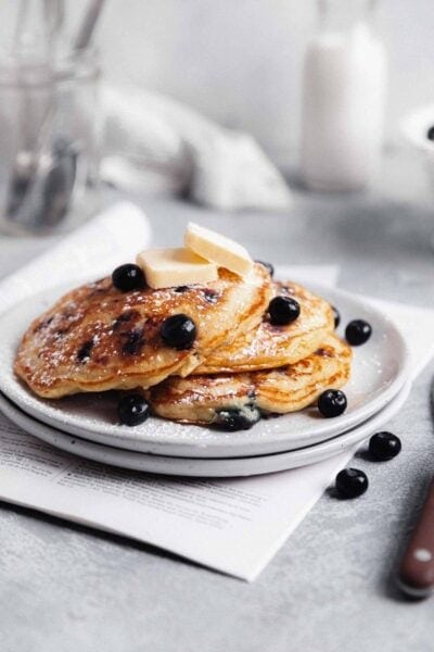 fluffy blueberry pancakes on a plate with maple syrup