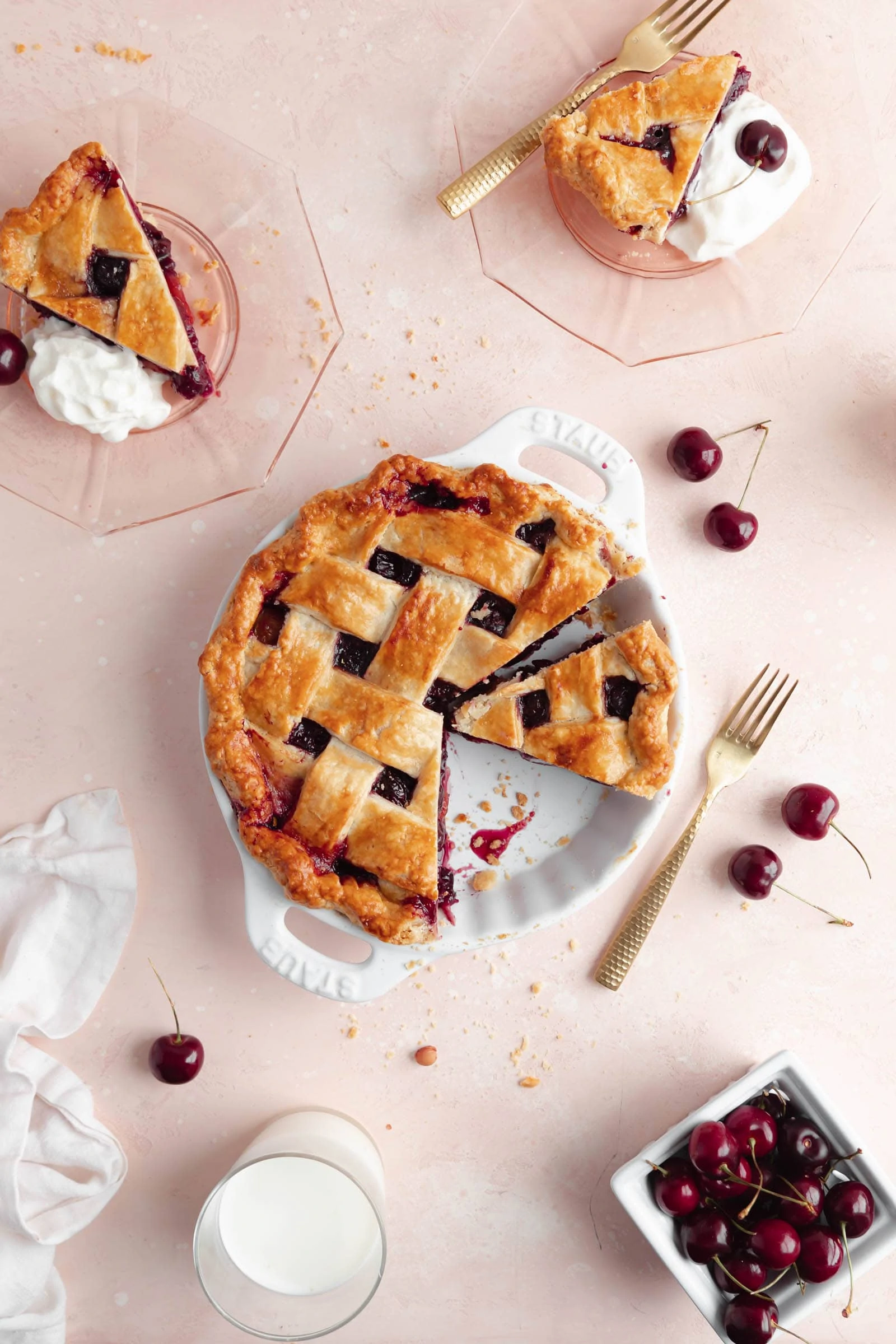 cherry pie with slices and cherries on a pink background