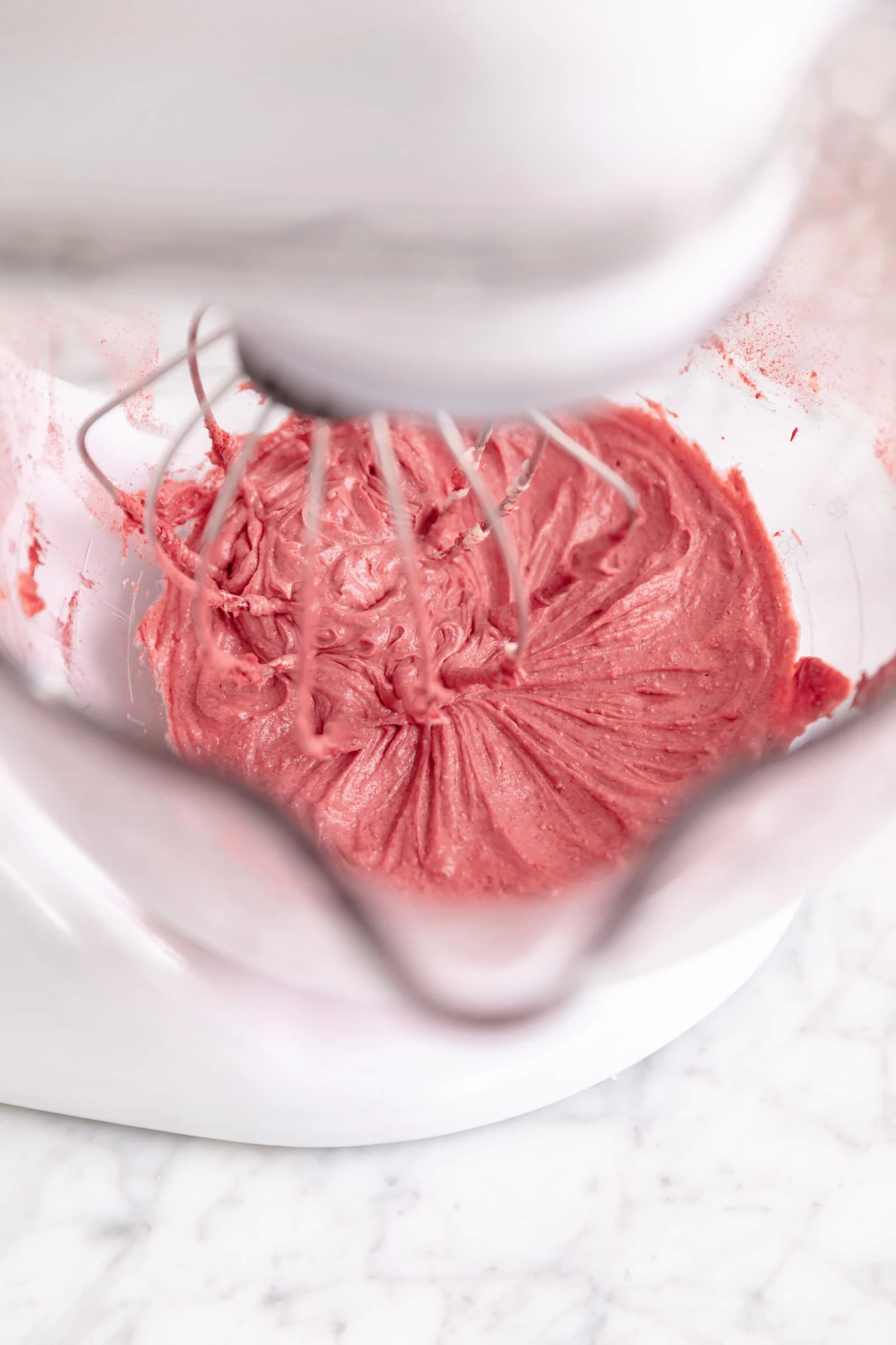 strawberry frosting in a bowl being whipped