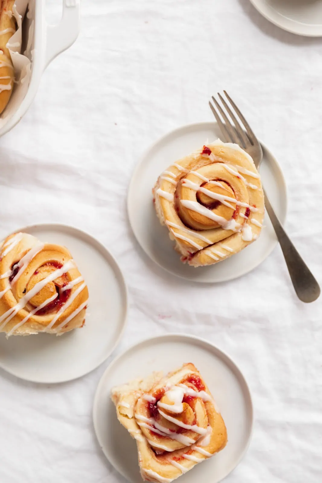 strawberry sweet rolls with icing on a white plate