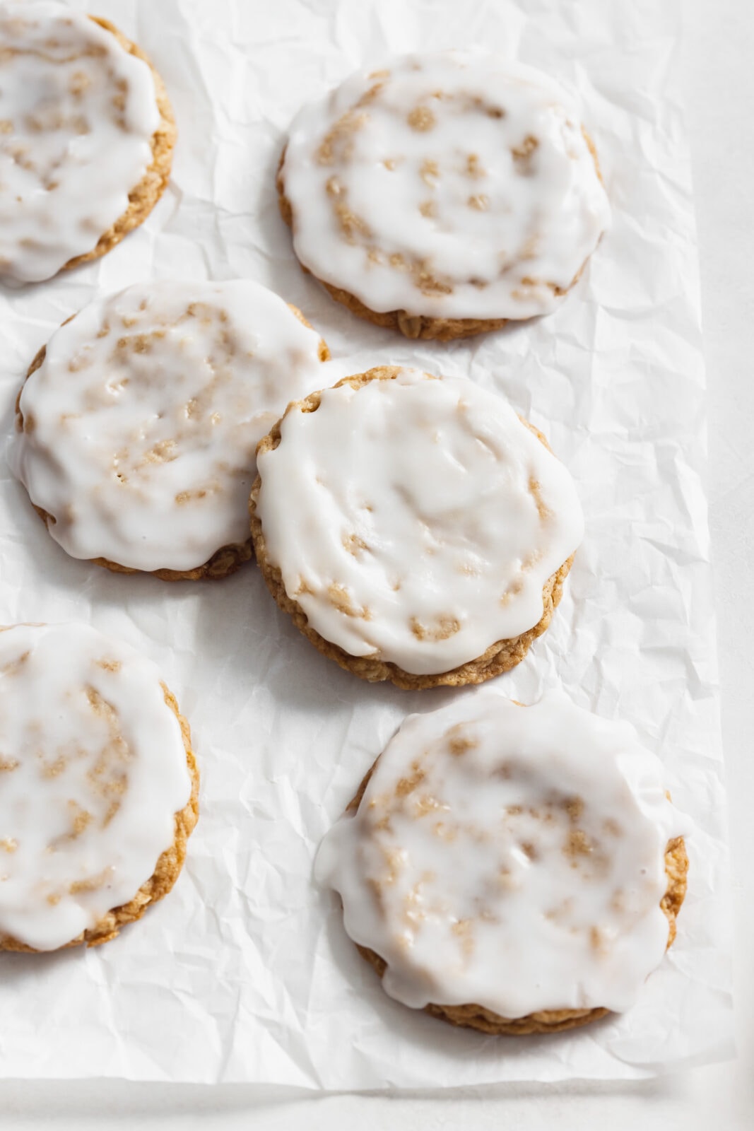 iced oatmeal cookies on parchment paper